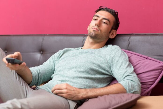 For Healthy Circulation, Avoid These 7 Poor Habits Man sitting on couch, TV remote in hand | sedentary lifestyle | How poor habits hurt circulation